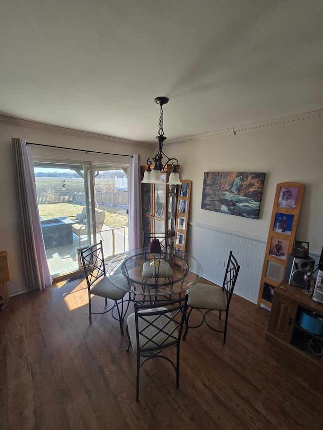 dining room with a notable chandelier, wood finished floors, and wainscoting