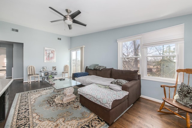 living area with visible vents, a ceiling fan, baseboards, and dark wood-style flooring