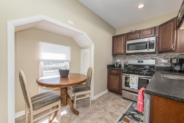 kitchen with stainless steel appliances, tasteful backsplash, dark countertops, and dark brown cabinetry