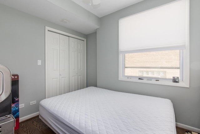 bedroom with a closet, dark wood-style floors, ceiling fan, and baseboards