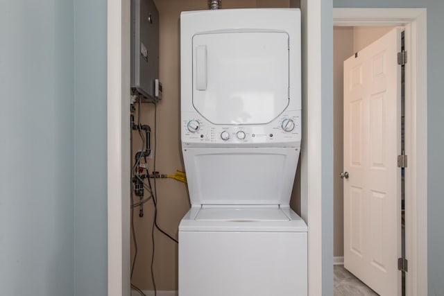 washroom with laundry area, water heater, and stacked washer / dryer