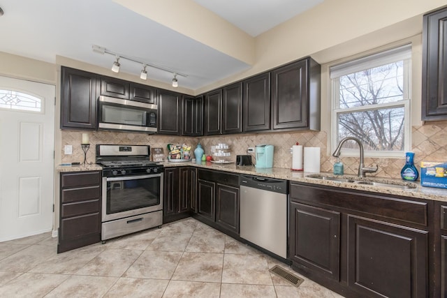 kitchen featuring a sink, stainless steel appliances, light stone countertops, and light tile patterned flooring