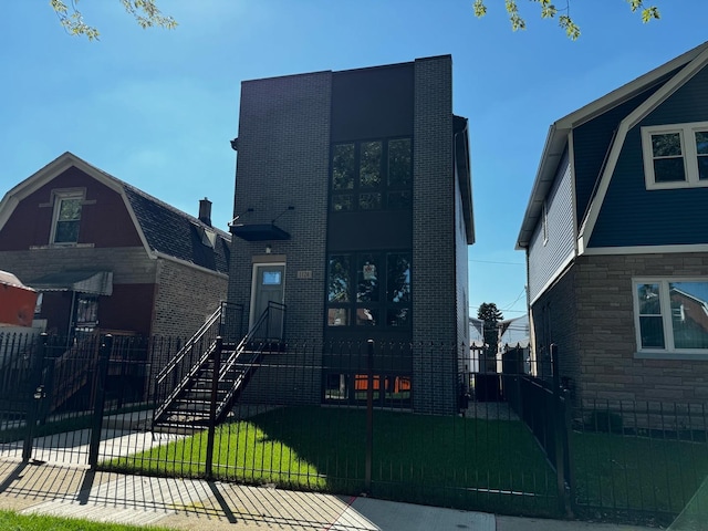 view of front of house featuring a front lawn, brick siding, and a fenced front yard