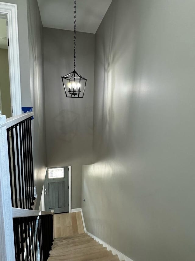 staircase with a high ceiling, a notable chandelier, and wood finished floors