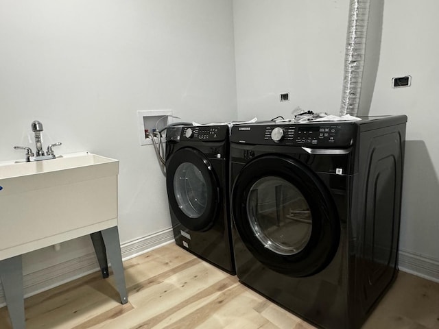 laundry area with washer and dryer, laundry area, light wood-style floors, and baseboards