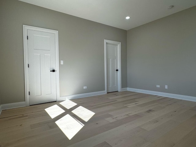 spare room featuring light wood-style flooring, recessed lighting, and baseboards