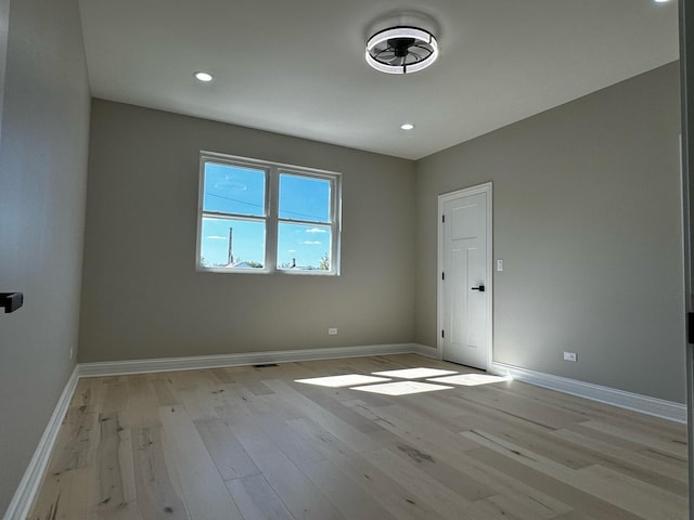 spare room featuring recessed lighting, light wood-type flooring, and baseboards