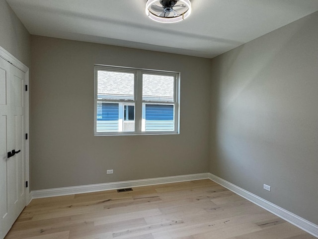 empty room with visible vents, light wood-style flooring, and baseboards