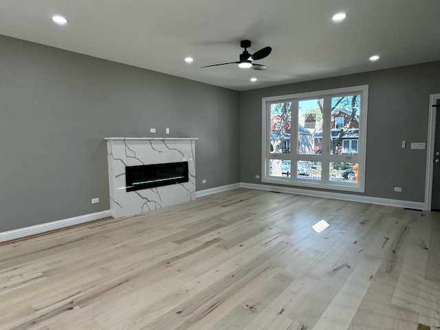 unfurnished living room featuring wood finished floors, recessed lighting, a fireplace, and baseboards