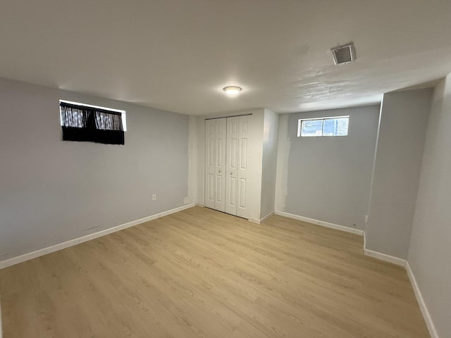 basement with visible vents, light wood-style flooring, and baseboards