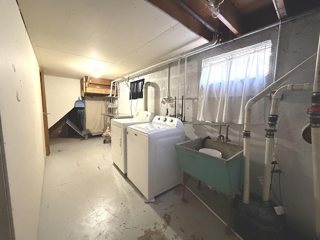 basement with washing machine and dryer, concrete block wall, and a sink