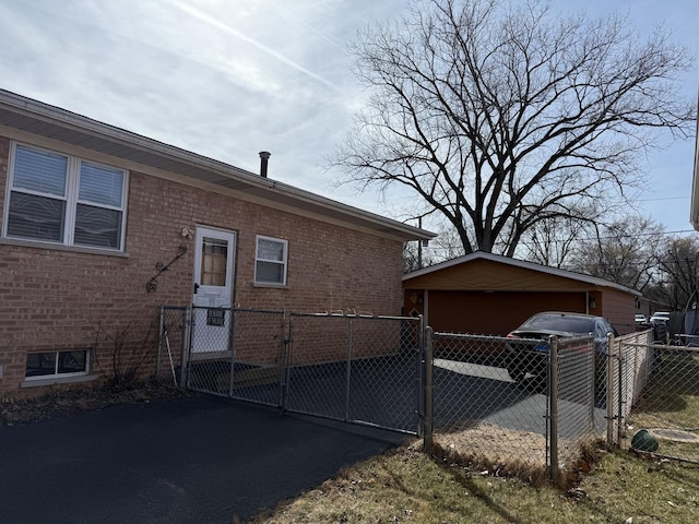 view of side of home featuring a detached garage, a gate, fence, and brick siding