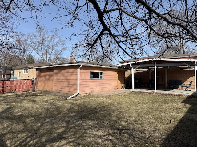 rear view of property with a lawn, a chimney, a patio, and fence