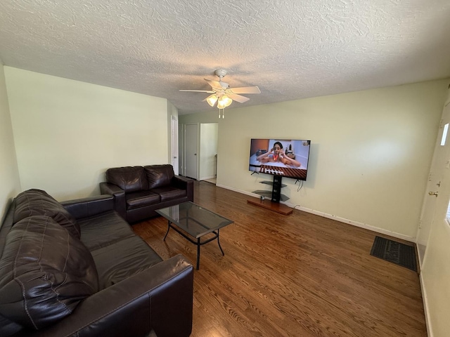 living room featuring wood finished floors, baseboards, visible vents, ceiling fan, and a textured ceiling