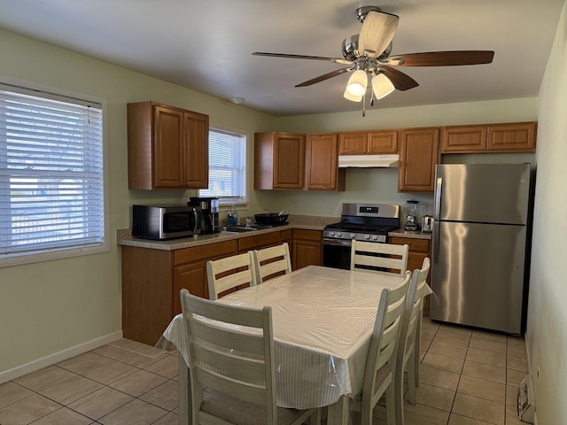 kitchen featuring ceiling fan, under cabinet range hood, light countertops, light tile patterned floors, and stainless steel appliances