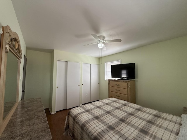 bedroom featuring two closets, ceiling fan, and wood finished floors