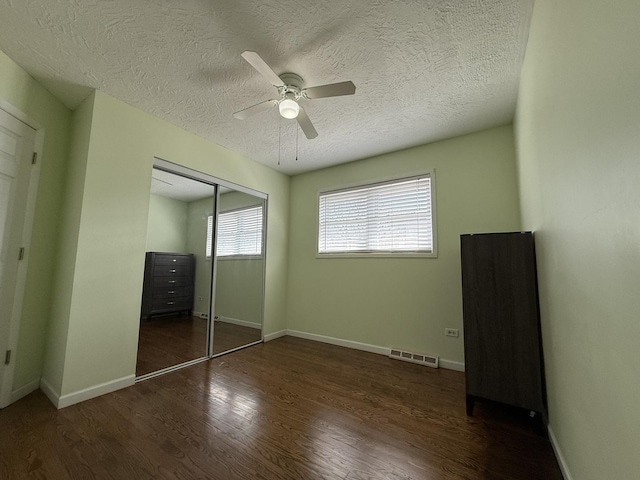 unfurnished bedroom with wood finished floors, visible vents, a closet, and baseboards