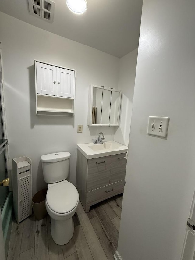 full bathroom featuring visible vents, toilet, vanity, and wood finished floors