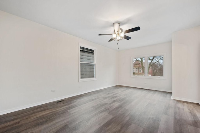 spare room featuring dark wood finished floors, visible vents, ceiling fan, and baseboards