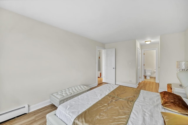 bedroom with ensuite bath, wood finished floors, baseboards, and a baseboard radiator