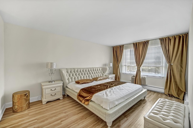 bedroom featuring baseboards, baseboard heating, and light wood-style flooring