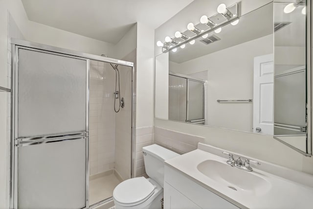 bathroom with vanity, toilet, visible vents, and a stall shower