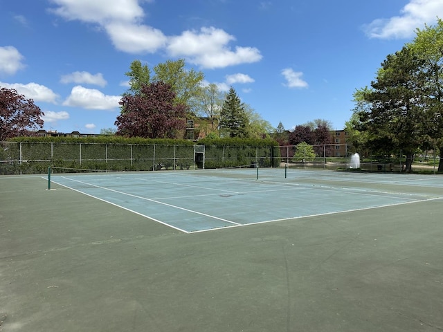 view of tennis court featuring community basketball court and fence