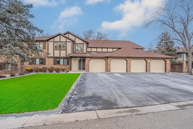 tudor home with brick siding, a shingled roof, a front lawn, stucco siding, and driveway