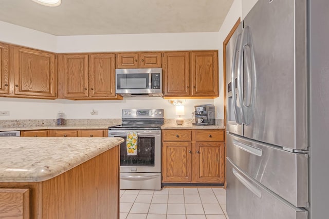 kitchen with light tile patterned floors, stainless steel appliances, and brown cabinets