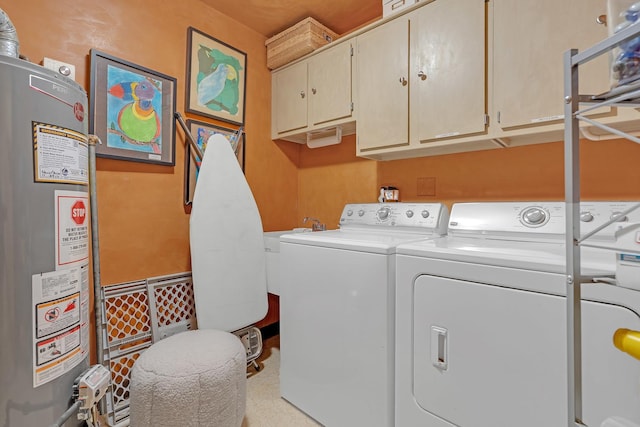 clothes washing area with cabinet space, gas water heater, and washer and dryer