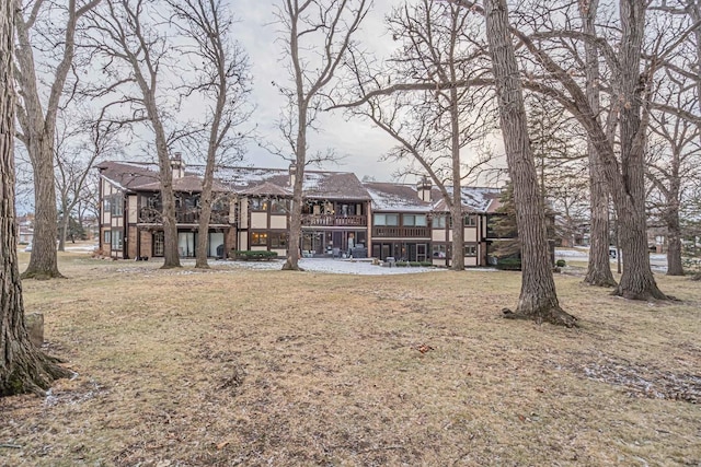 back of property with a lawn and a chimney