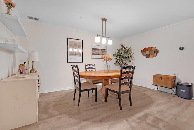 dining room featuring visible vents, light wood-style flooring, baseboards, and ornamental molding