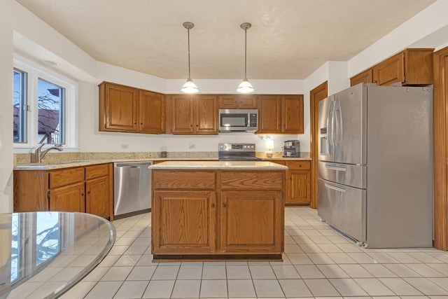 kitchen with light tile patterned floors, a sink, hanging light fixtures, appliances with stainless steel finishes, and brown cabinets