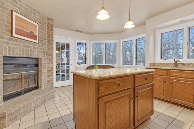 kitchen featuring light stone counters, light tile patterned flooring, a fireplace, and a sink