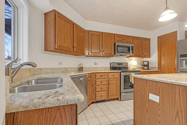 kitchen with light tile patterned flooring, a sink, stainless steel appliances, pendant lighting, and brown cabinets