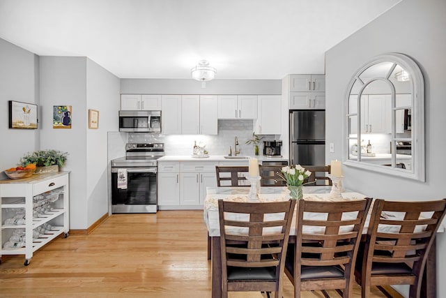 kitchen with tasteful backsplash, light wood-type flooring, light countertops, stainless steel appliances, and a sink