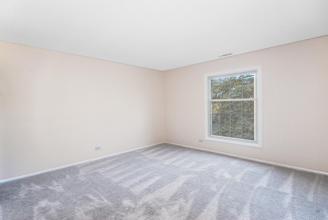 carpeted spare room with visible vents and baseboards