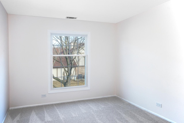 carpeted empty room featuring baseboards and visible vents