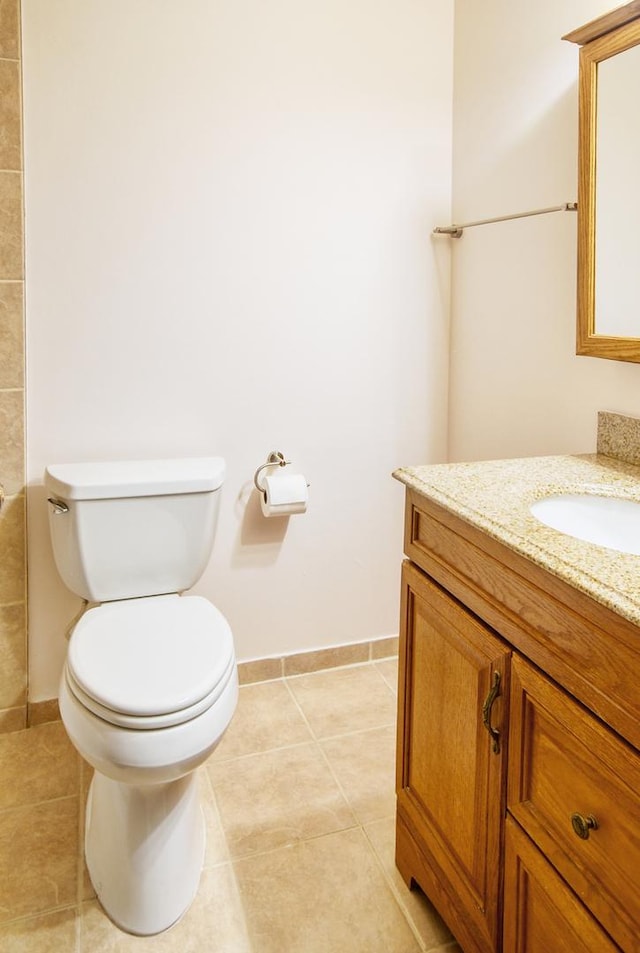 bathroom with tile patterned flooring, toilet, vanity, and baseboards