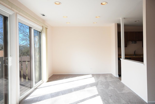 spare room featuring visible vents, baseboards, carpet, recessed lighting, and a sink