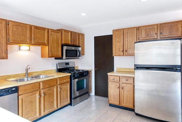 kitchen with light countertops, brown cabinetry, appliances with stainless steel finishes, and a sink