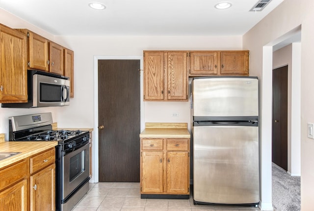 kitchen featuring light tile patterned floors, visible vents, stainless steel appliances, light countertops, and brown cabinets