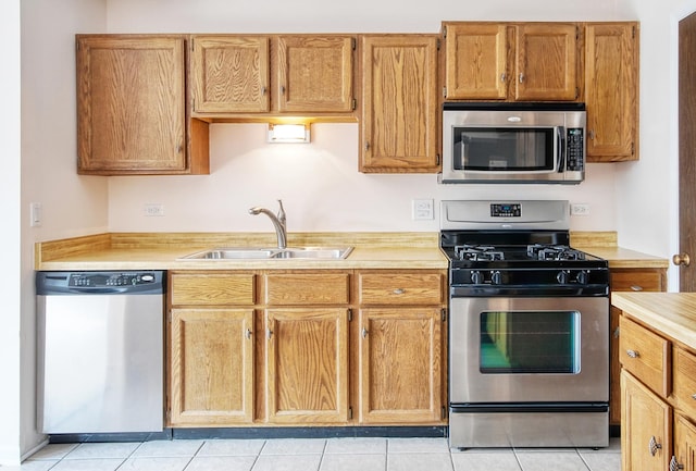 kitchen featuring brown cabinetry, appliances with stainless steel finishes, light countertops, and a sink