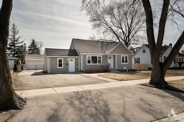 view of front of house with a garage, an outbuilding, a shingled roof, and fence