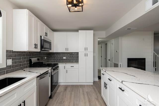 kitchen with light wood finished floors, visible vents, backsplash, and stainless steel appliances