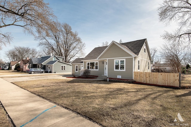 bungalow-style home featuring roof with shingles, a front lawn, and fence