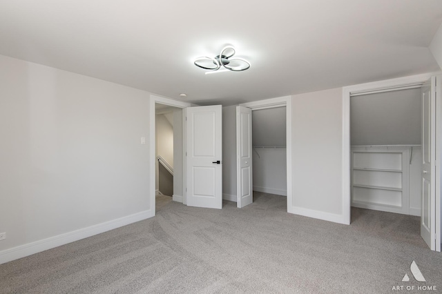 unfurnished bedroom with two closets, carpet, and baseboards