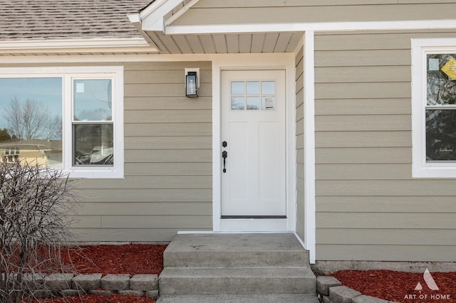 view of exterior entry featuring a shingled roof