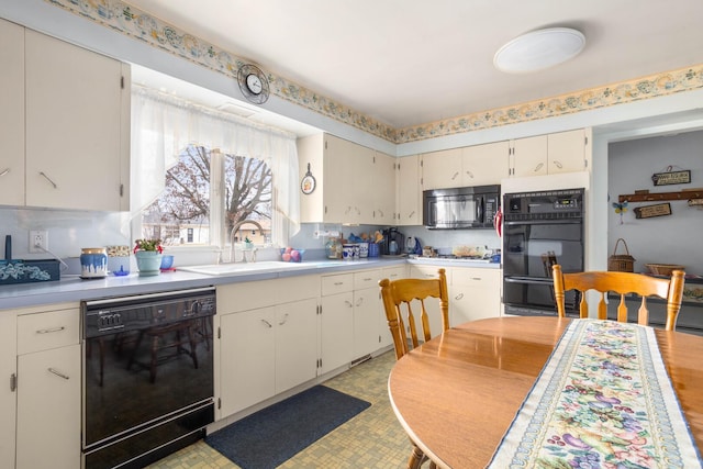 kitchen featuring black appliances, light countertops, light floors, and a sink