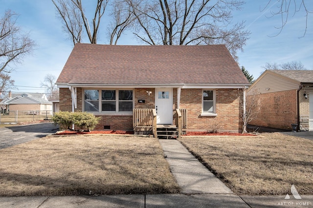 view of front facade featuring crawl space, brick siding, a front lawn, and a shingled roof